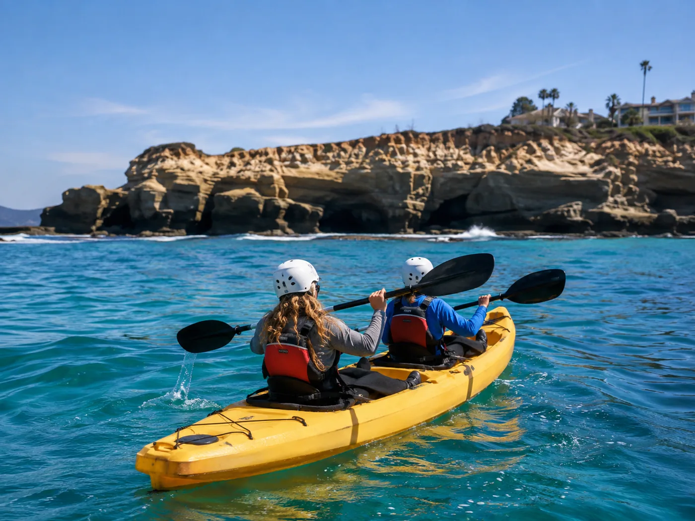 Two paddlers in a tandem kayak heading toward the caves